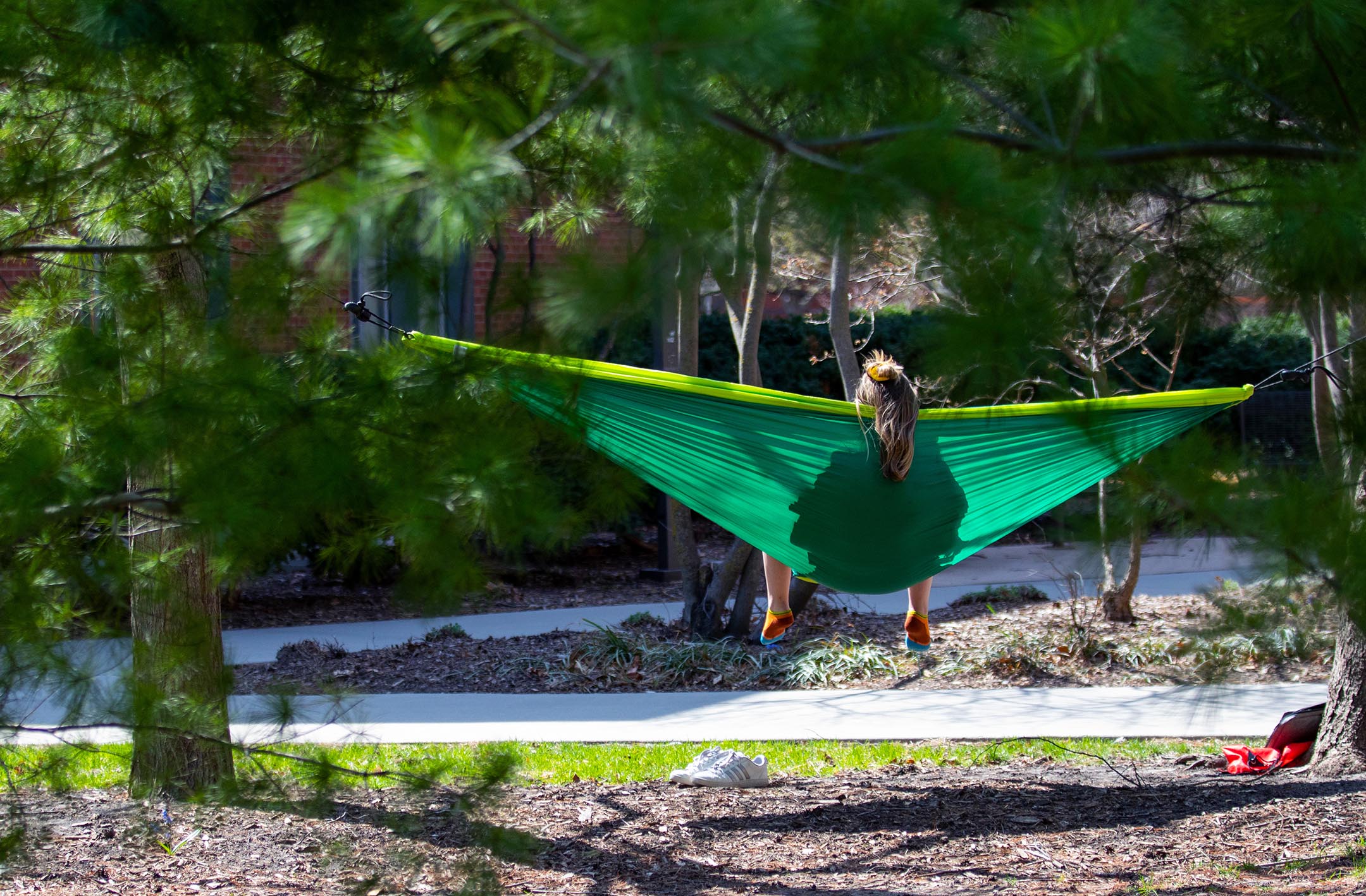 A student hammocking on a sunny day.