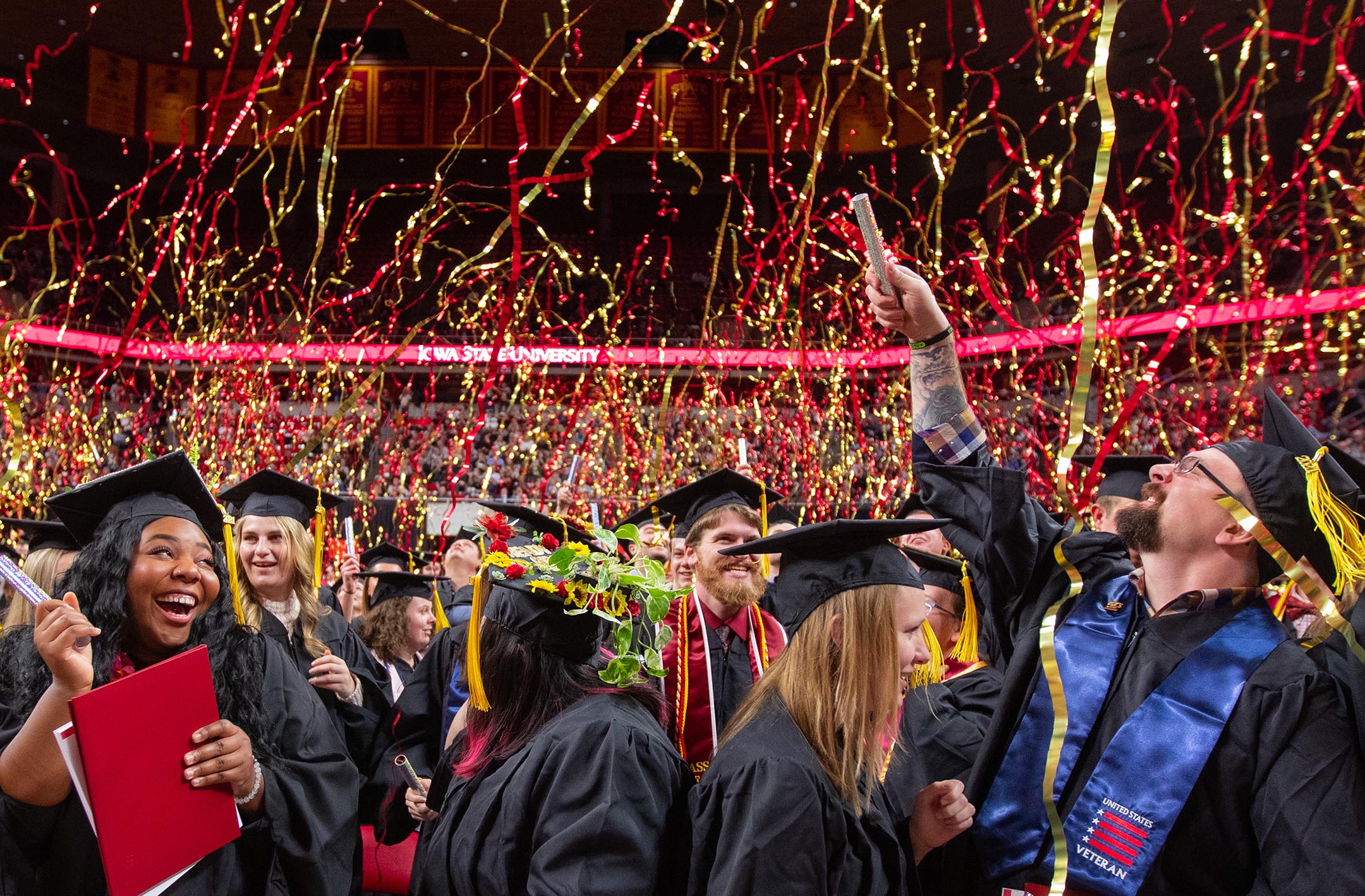 Graduates excitedly celebrate the conclusion of commencement as streamers fall around them.