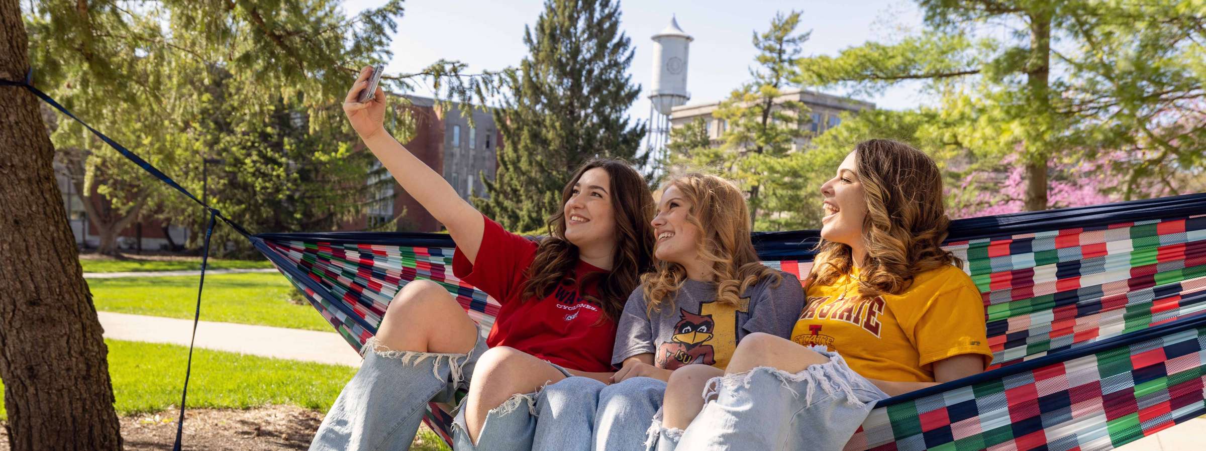 Three students sitting in a hammock taking a selfie