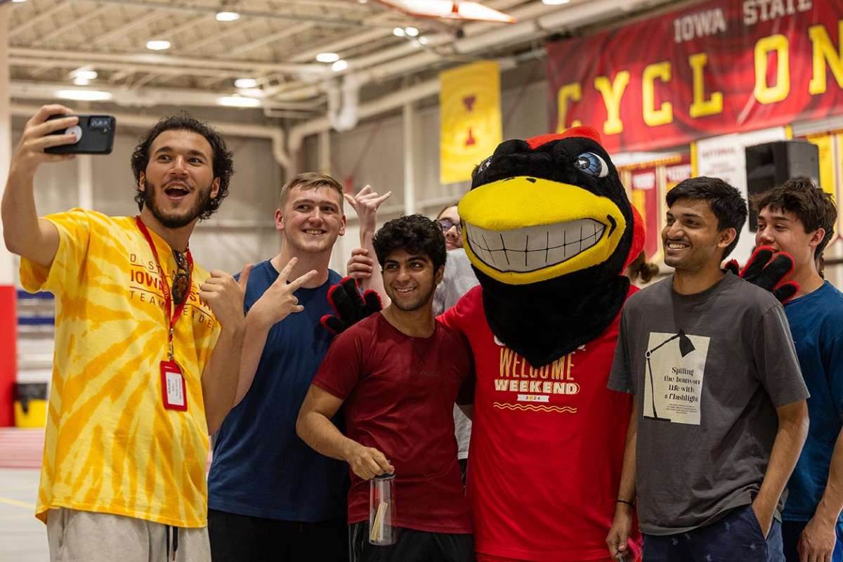 Group of students pose for a selfie with Cy the mascot.