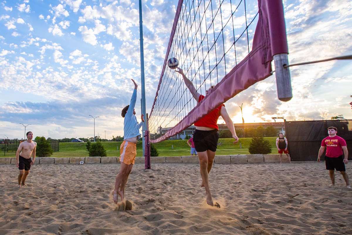 Play at the net during a sand volleyball game near sunset.