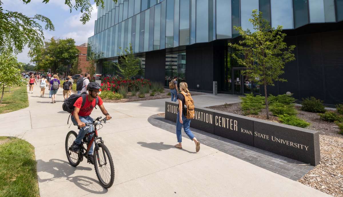 Student riding bike and other students walking in front of the Student Innovation Center