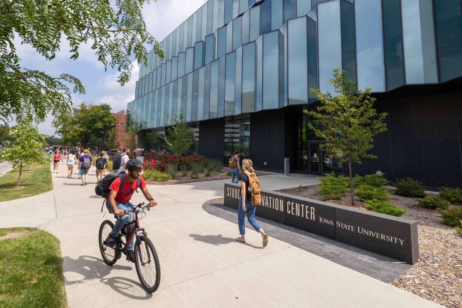 Students walking and biking in front of the Student Innovation Center